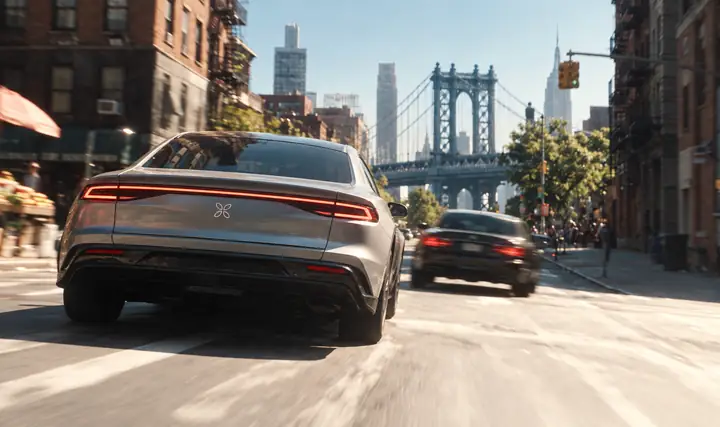 A police car races down a city street toward a bridge.